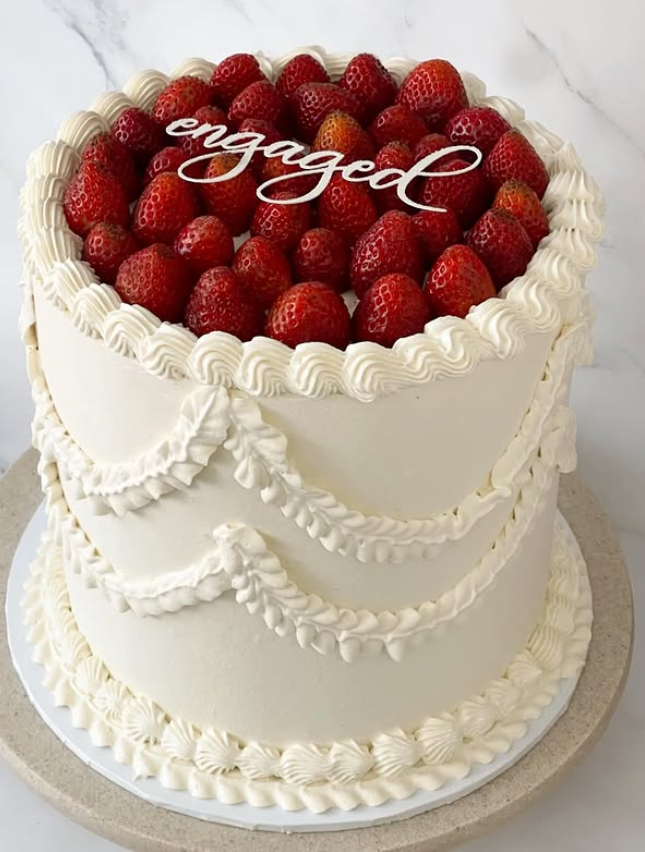 Vintage piped celebration cake topped with fresh strawberries and 'engaged' topper