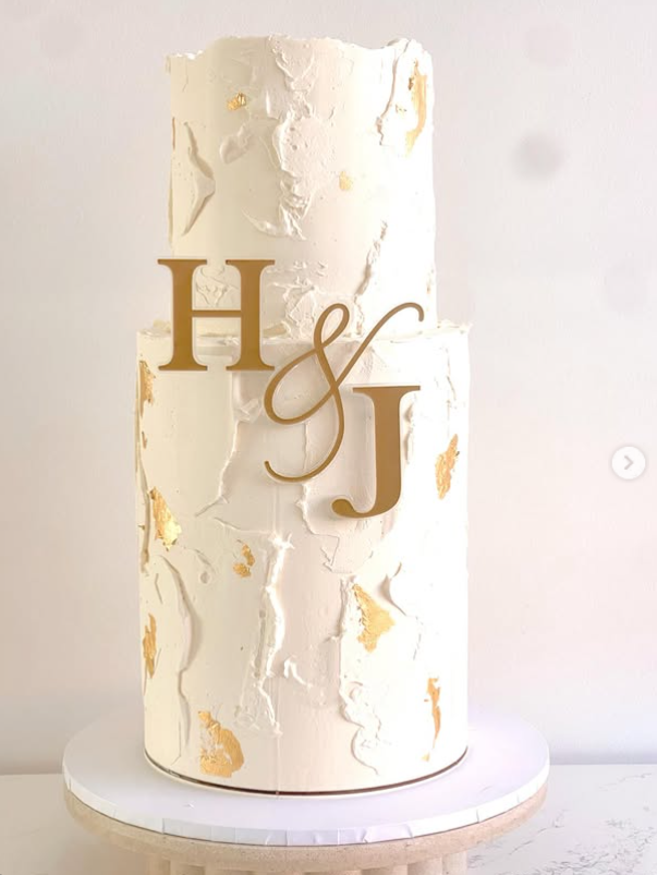 Two-tier textured white celebration cake with gold leaf and H&J monogram