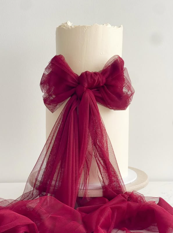 Minimal ivory celebration cake with deep red tulle bow drape
